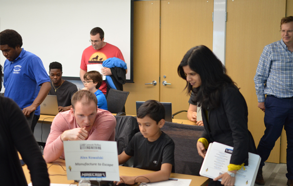 CMU MechE Department Head Allen Robinson looks on as students discuss a game where one needs to manufacture items to escape a labyrinth